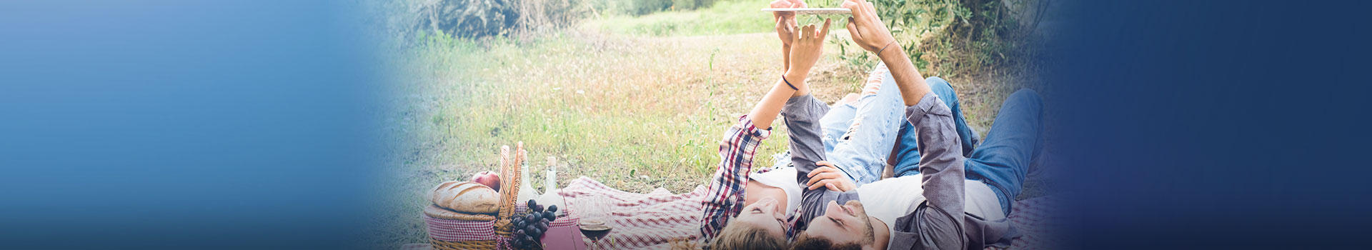 Young couple on picnic blanket looking at something on mobile phone
