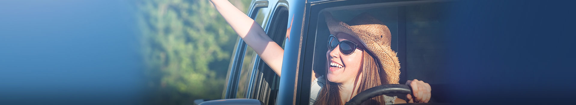 young woman waving out car window while driving