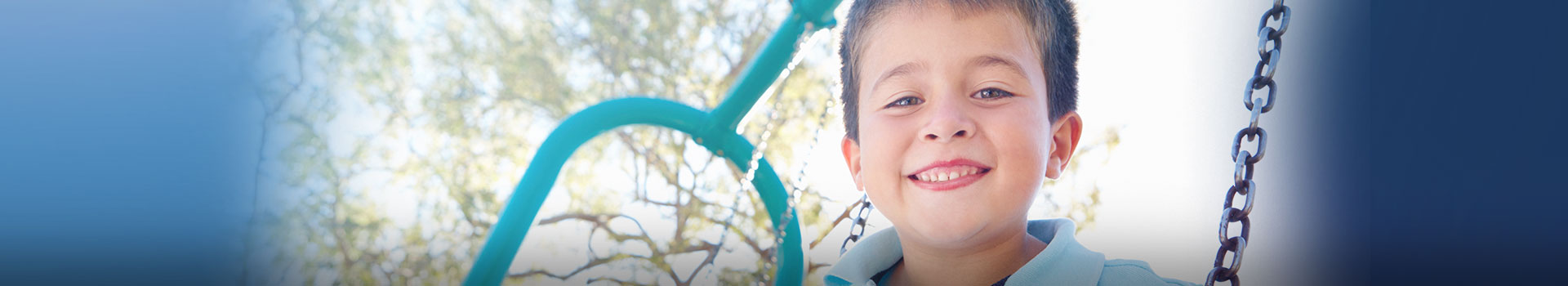 Young boy smiling on swing at playground